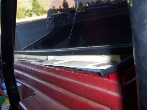 1991 Ford Bronco - Interior view of a red vehicle, with a reflection of a large tire in the rear window.