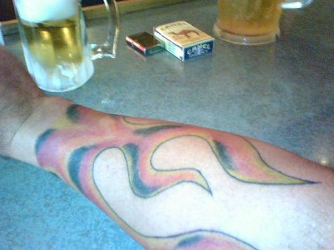 1995 Ford Bronco - A close-up of a flame tattoo on an arm, with a pack of Camel cigarettes and two mugs of beer visible.