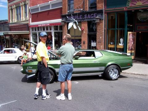 1972 Ford Ranchero - A green muscle car is parked on a street with two men standing beside it, and another car in the background.