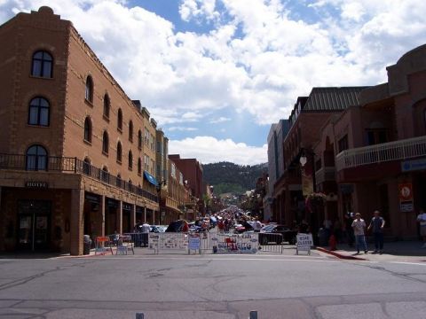 1972 Ford Ranchero - A street lined with buildings and parked cars, with barriers and signs indicating a road closure.