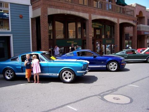 1972 Ford Ranchero - Three classic Ford Mustangs are parked on a street in front of buildings.