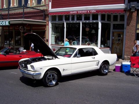 1972 Ford Ranchero - White 1965 Ford Mustang coupe parked on street with hood open, next to a red convertible.