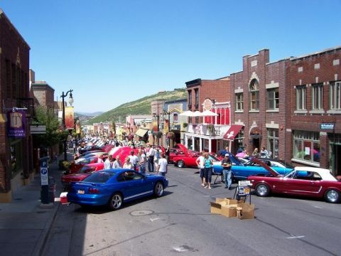 1972 Ford Ranchero - A street filled with classic cars on a sunny day, with people milling around.