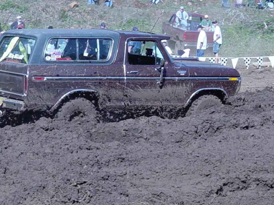 Brown full-size SUV plowing through deep mud at an off-road event