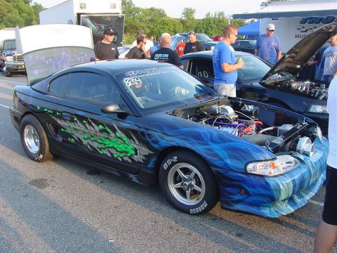 1986 Ford Mustang - Customized Ford Mustang with flame graphics and racing slicks on display at an event.