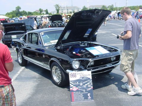 1986 Ford Mustang - A black 1968 Shelby GT500 KR Mustang is displayed with its hood open at an outdoor car show.