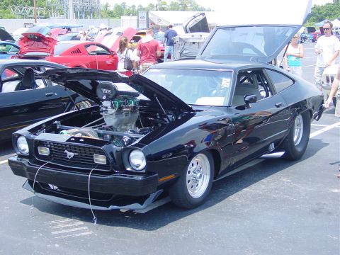 1986 Ford Mustang - Customized black Ford Mustang with a powerful engine on display at an outdoor car show.