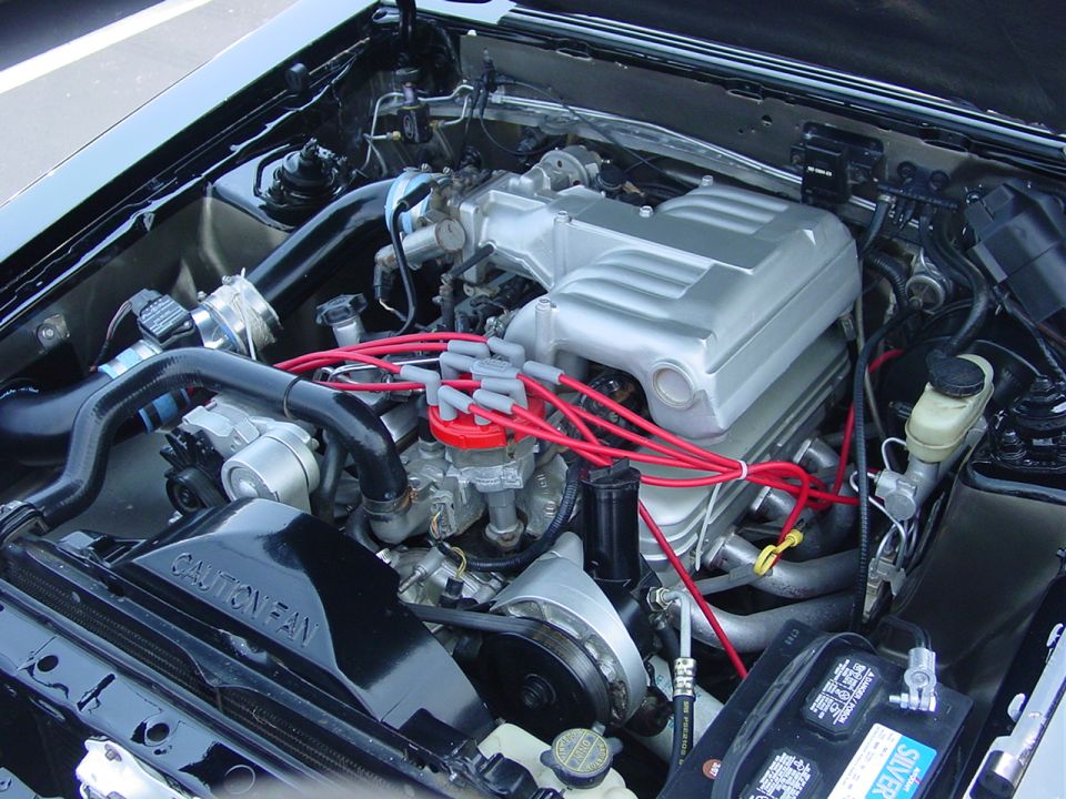 1986 Ford Mustang engine bay with silver intake manifold and red spark plug wires