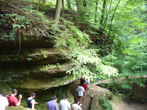 1991 Ford Probe - A group of people are hiking on a trail through a wooded area with prominent rock formations.