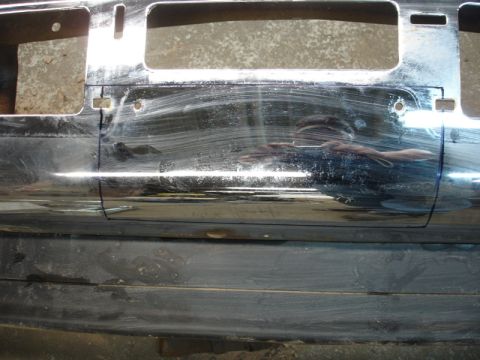 1996 Ford Bronco - Close-up view of a chrome bumper section, possibly for a winch installation, showing two large rectangular cutouts and numerous scratches.