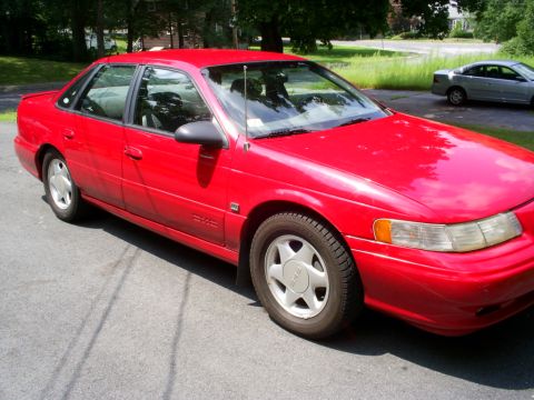 1995 Ford Taurus - Red 1995 Ford Taurus sedan parked outdoors with another car in the background.