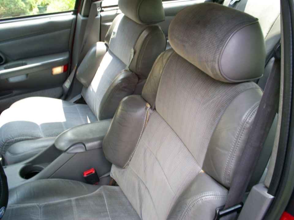 Interior of a 1995 Ford Taurus showing front bucket seats with grey fabric and leather trim, center console, and door panel
