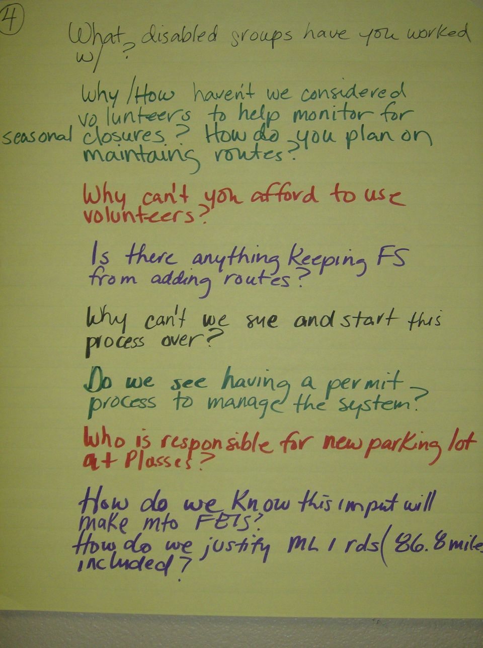 Yellow pad with handwritten questions about disabled groups, volunteers, routes, and parking lots. Bottom right has a SuperMotors logo
