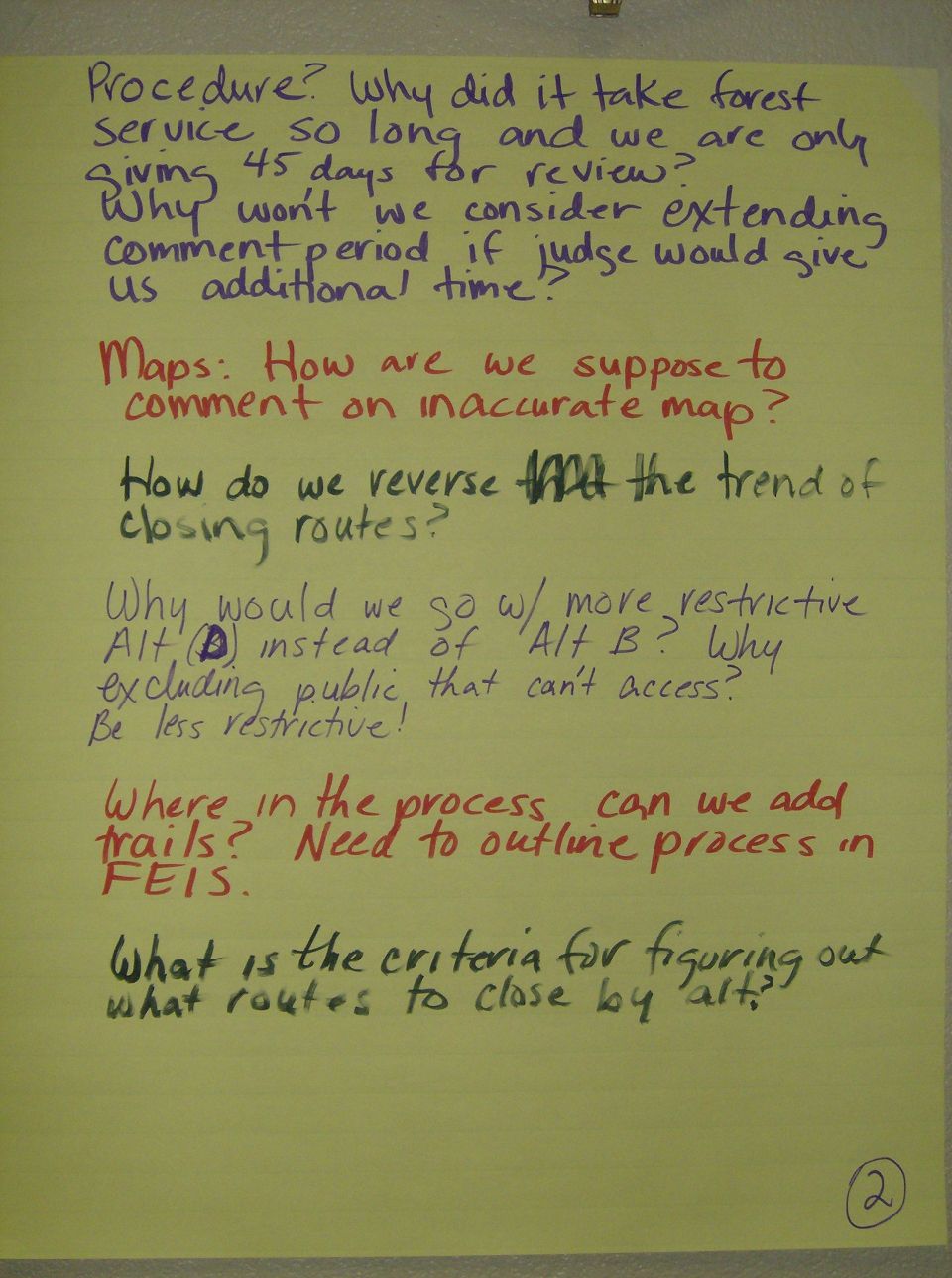 Yellow poster paper with handwritten text in purple, red, and black ink. Text discusses procedure, maps, and criteria