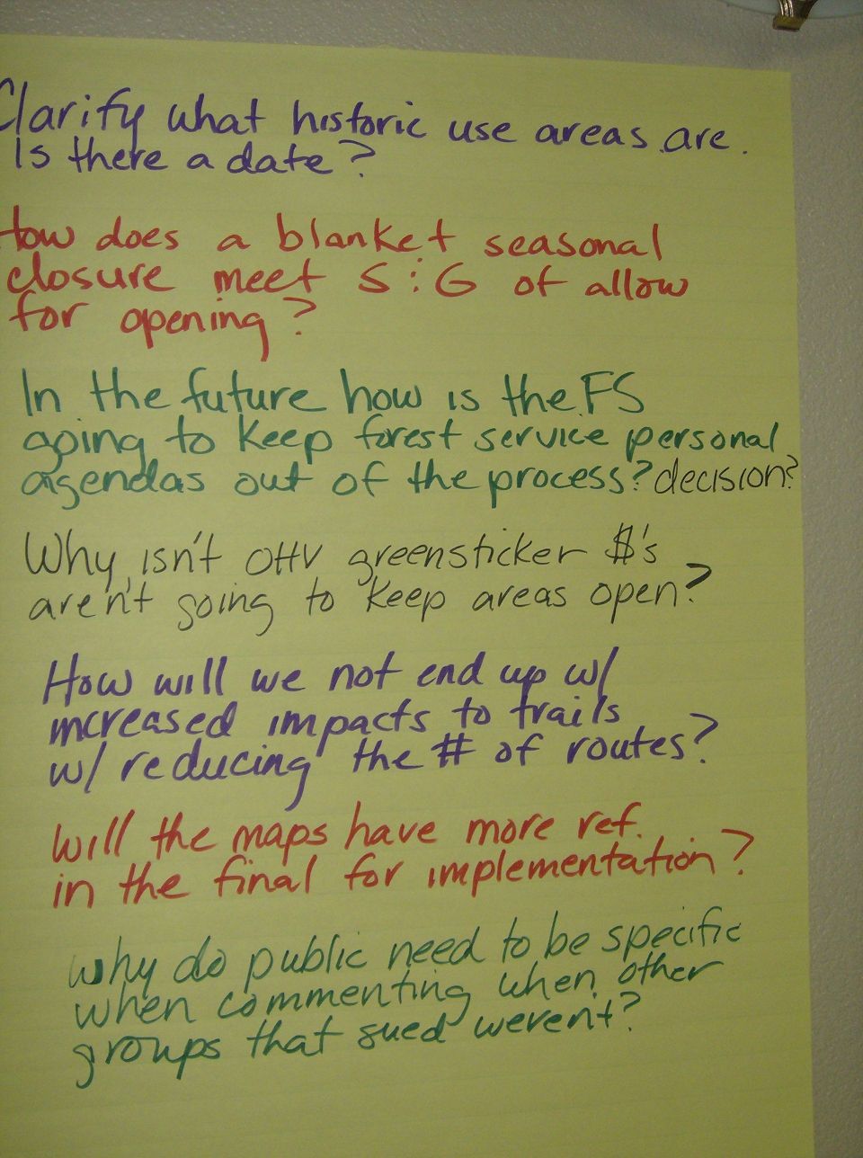 Yellow poster board with handwritten questions about forest service policies and trail usage