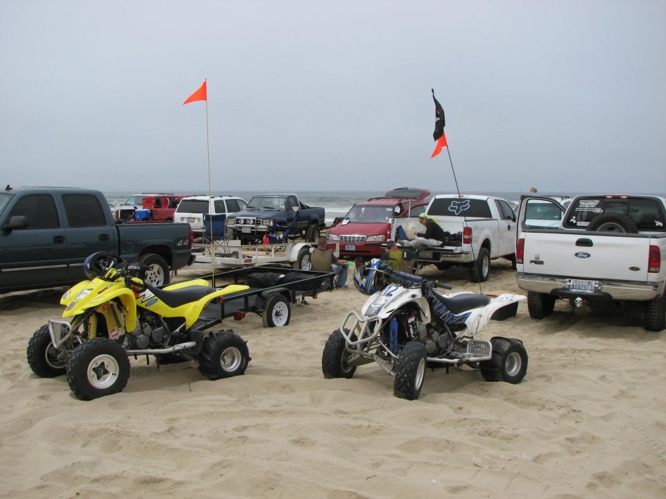 ATVs and pickup trucks with flags parked on a beach