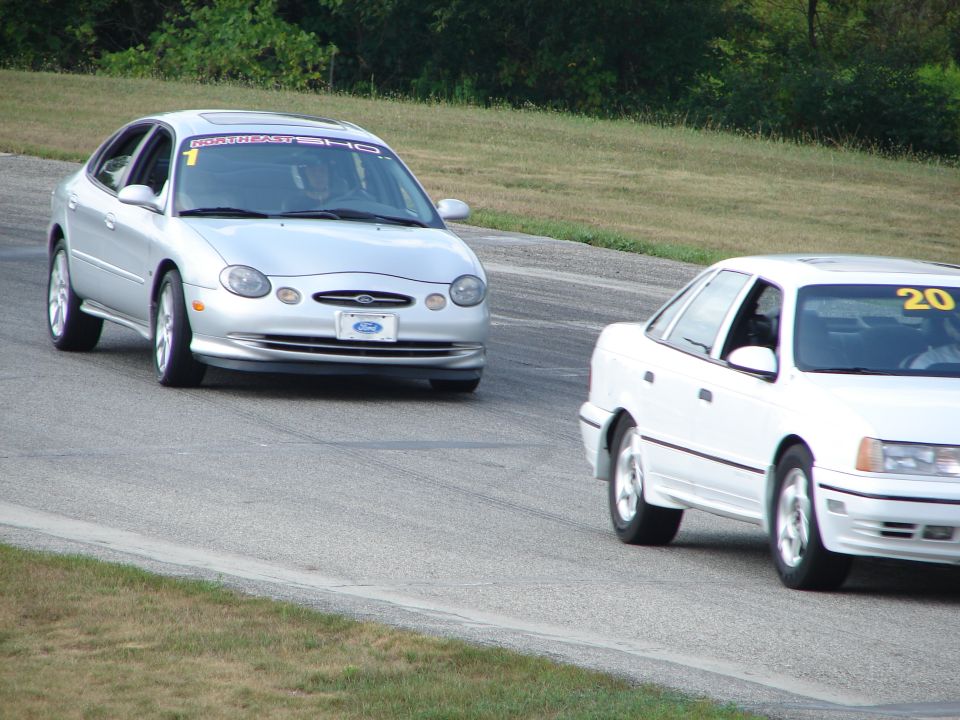 Silver 1996 Ford Taurus on race track with "NORTHEAST SHO" banner