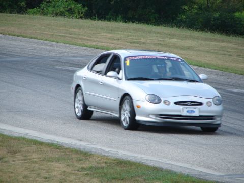 1993 Ford Taurus - Silver Ford Taurus on a race track, likely a later generation than 1993.