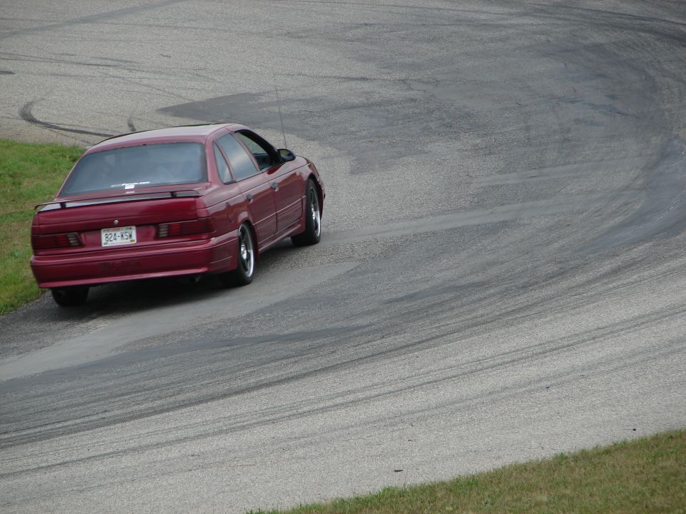 Red 1993 Ford Taurus on a race track, rear view
