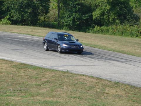 1993 Ford Taurus - A dark blue Subaru Legacy wagon navigates a turn on a race track, displaying the number 03 on its windshield.