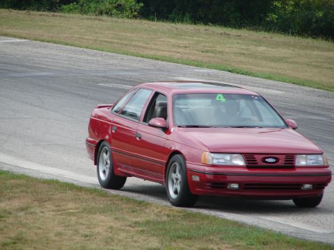 1993 Ford Taurus - Red 1993 Ford Taurus seen on a road course with a racing number on its windshield.