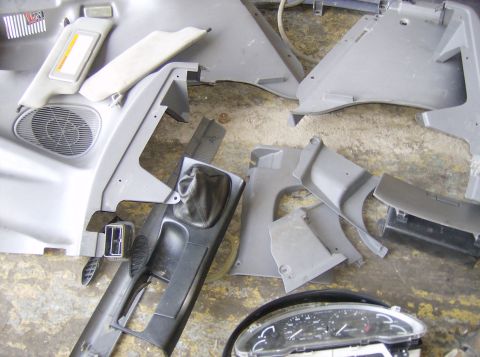 1996 Ford Probe - Various interior car parts are disassembled and scattered on a concrete floor.