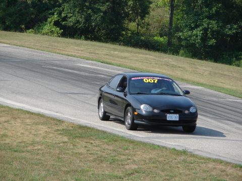 1993 Ford Taurus - Black Ford Taurus on a race track, with a '007' banner on the windshield.