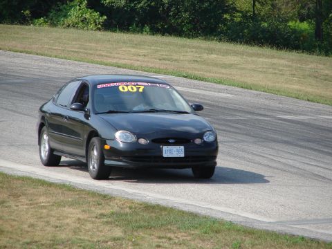 1993 Ford Taurus - A black sedan, likely a 1996 Ford Taurus, navigates a turn on a race track.