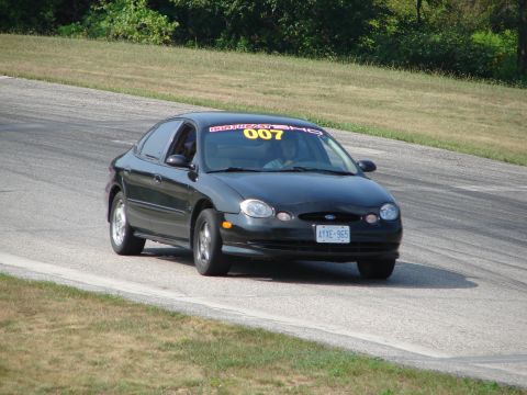 1993 Ford Taurus - Black 1993 Ford Taurus seen on a road course with a racing banner on the windshield.