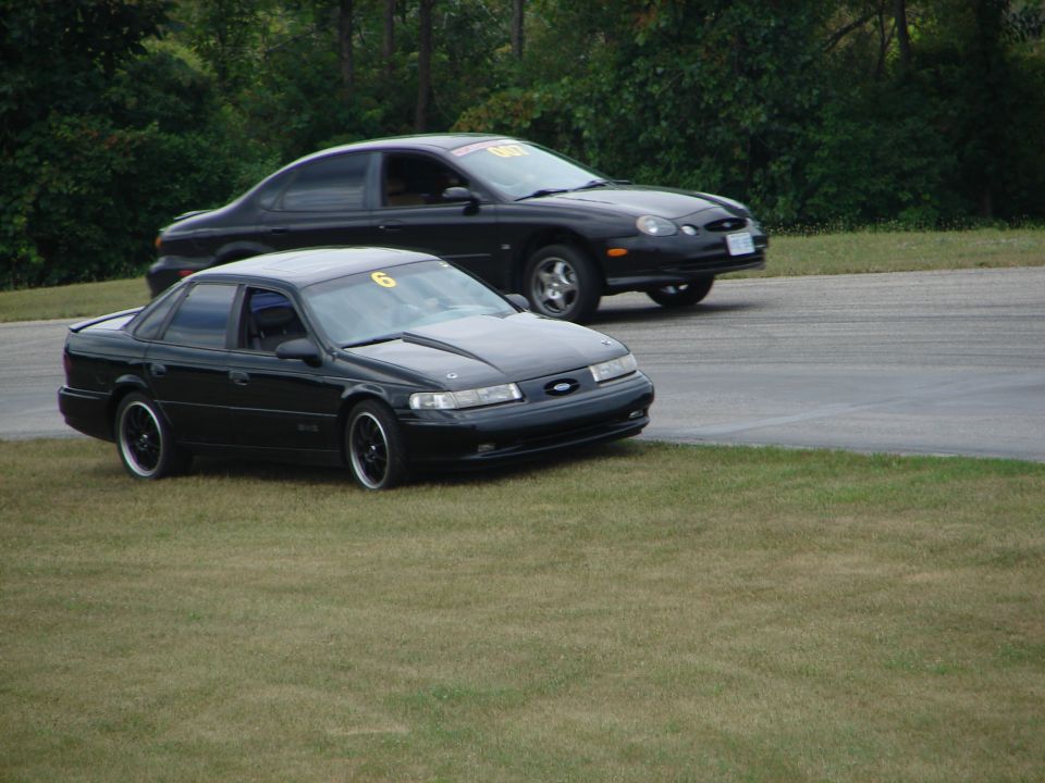 Two black sedans, one with a number 6 on the windshield, on a race track