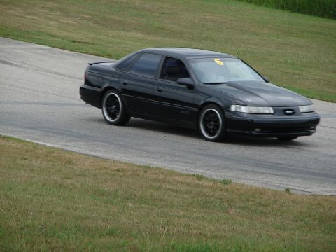 1993 Ford Taurus - Black 1993 Ford Taurus seen on a road course with a racing number on the windshield.