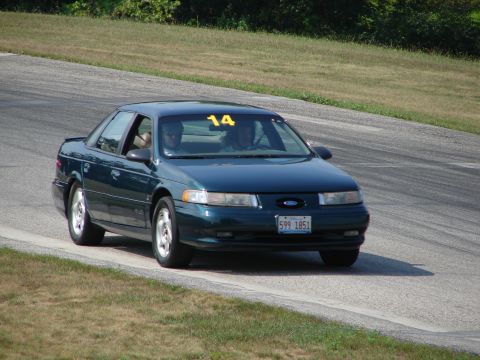 1993 Ford Taurus - A 1993 Ford Taurus is seen on a race track, identified by its body style and license plate.