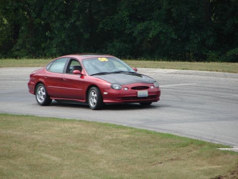 1993 Ford Taurus - Red 1993 Ford Taurus with a black hood and racing number 08 navigates a turn on a road course.