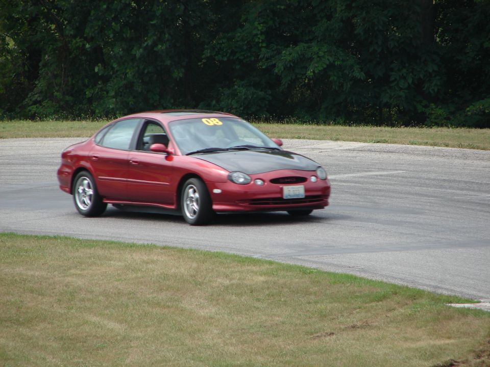 1993 Ford Taurus on a race track, red with black hood and racing number 08