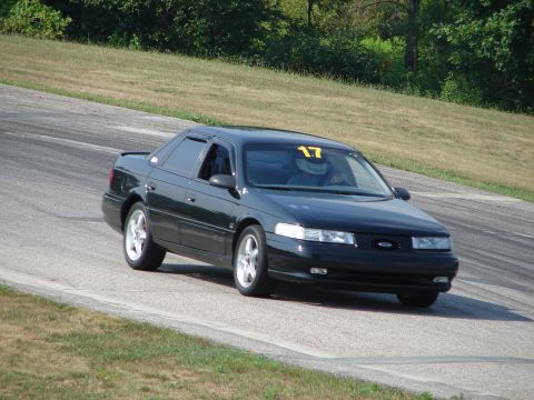 1993 Ford Taurus - Black 1993 Ford Taurus driving on a road course with a racing number on the windshield.