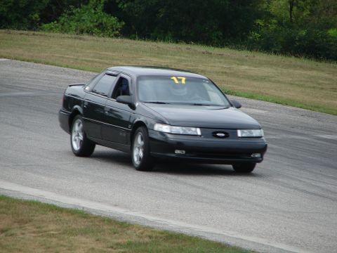 1993 Ford Taurus - A black sedan with racing number 17 navigates a turn on a road course.