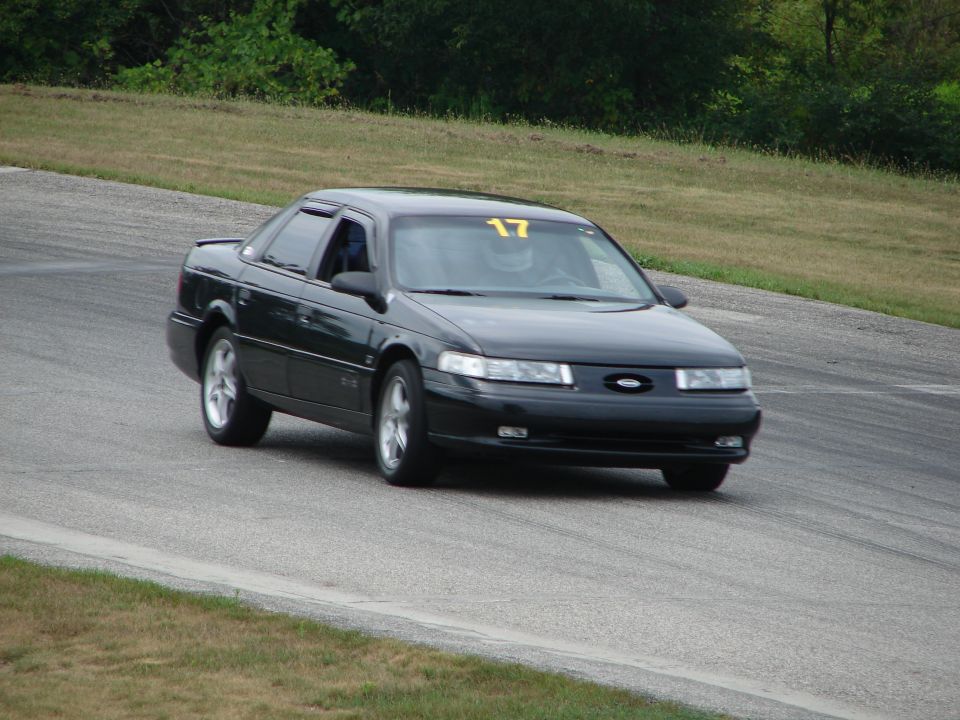 Black sedan with racing number 17 on windshield, driving on a road course