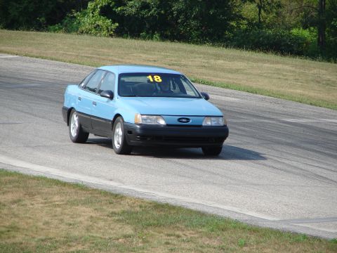 1993 Ford Taurus - 1993 Ford Taurus on a road course, showing its distinctive body style and race number.