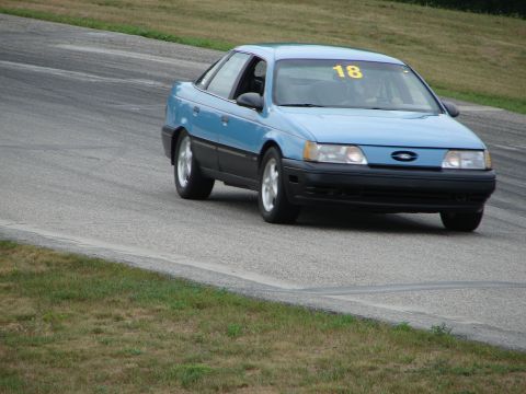 1993 Ford Taurus - A blue 1993 Ford Taurus competes on a road course, displaying the number 18 on its windshield.