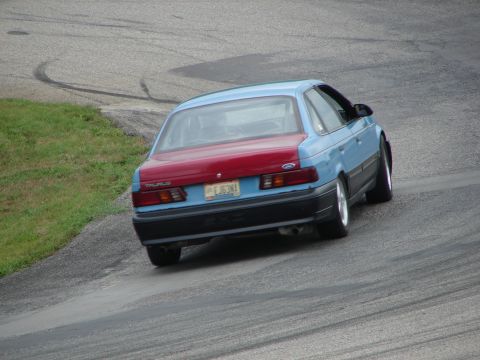 1993 Ford Taurus - A two-tone Ford Taurus navigates a turn on a road course.