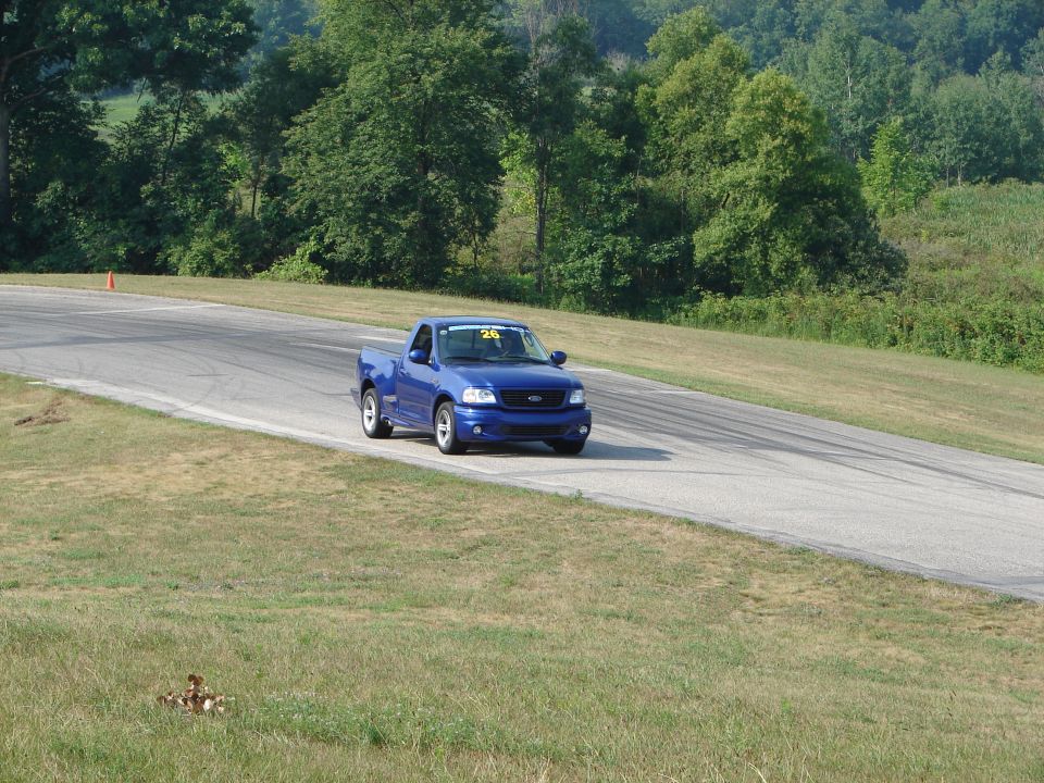 Blue 2001 Ford F-150 SVT Lightning pickup truck on a road course, number 26 on windshield