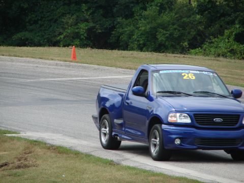 1993 Ford Taurus - Blue Ford F-150 Lightning pickup truck seen on a race track with an orange cone in the background.