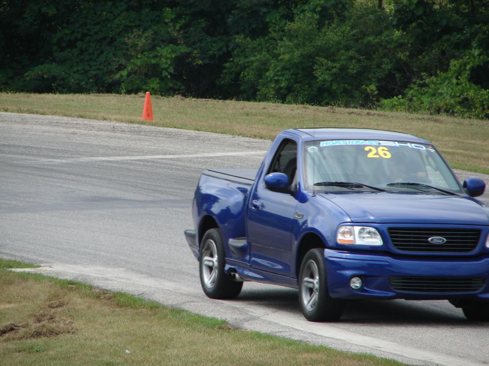 Blue 1999 Ford F-150 Lightning pickup truck with number 26 on windshield, on a race track