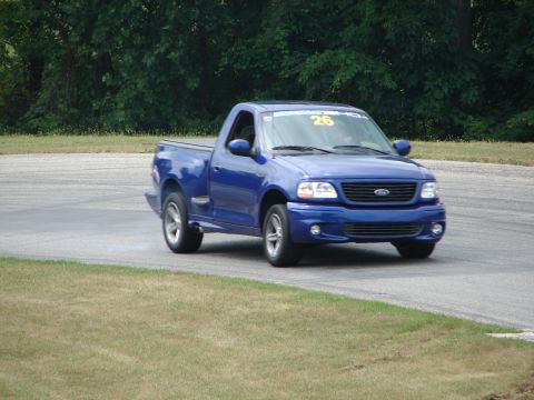 1993 Ford Taurus - A blue pickup truck is seen on a race track, with a number 26 visible on its windshield.