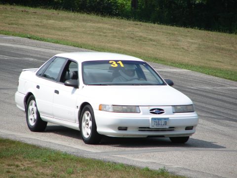 1993 Ford Taurus - White Ford Taurus with racing number 31 on windshield navigates a turn on a road course.