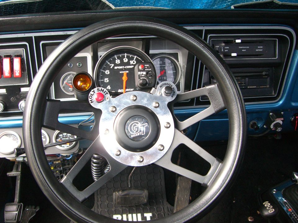 Grant GT steering wheel with Holy Shit and Nitrous Purge buttons, Auto Meter tach on modified truck dash
