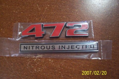 1977 Ford F-150 - Two automotive emblems, one reading '472' and the other 'Nitrous Injected'.