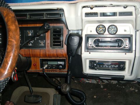 1981 Ford Bronco - The interior of a 1980s Ford Bronco features a wood-grain dash with multiple gauges and aftermarket electronics.