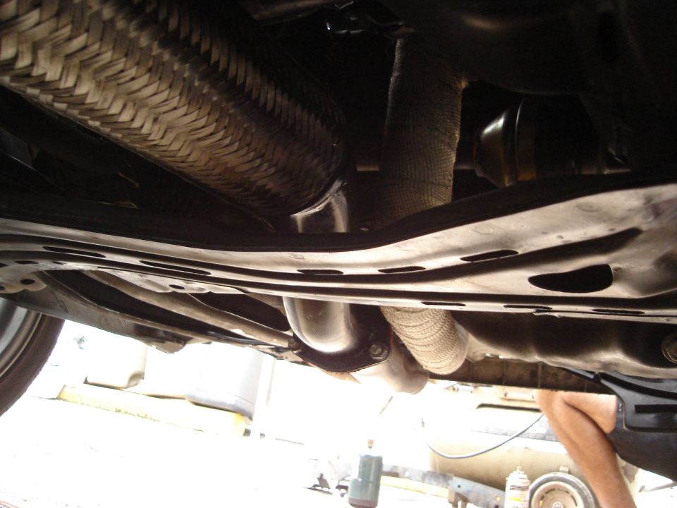 Underside of a vehicle showing exhaust pipes and heat wrap