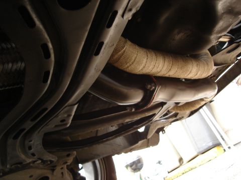 1995 Mazda MX-6 - Custom exhaust modification with heat wrap visible on the underside of a vehicle.